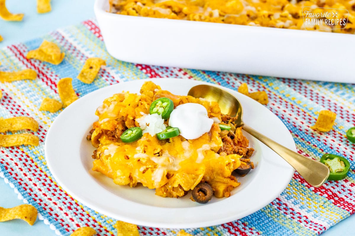 Frito Chili Pie with a dollop of sour cream, sliced jalapeño, and onions on top.
