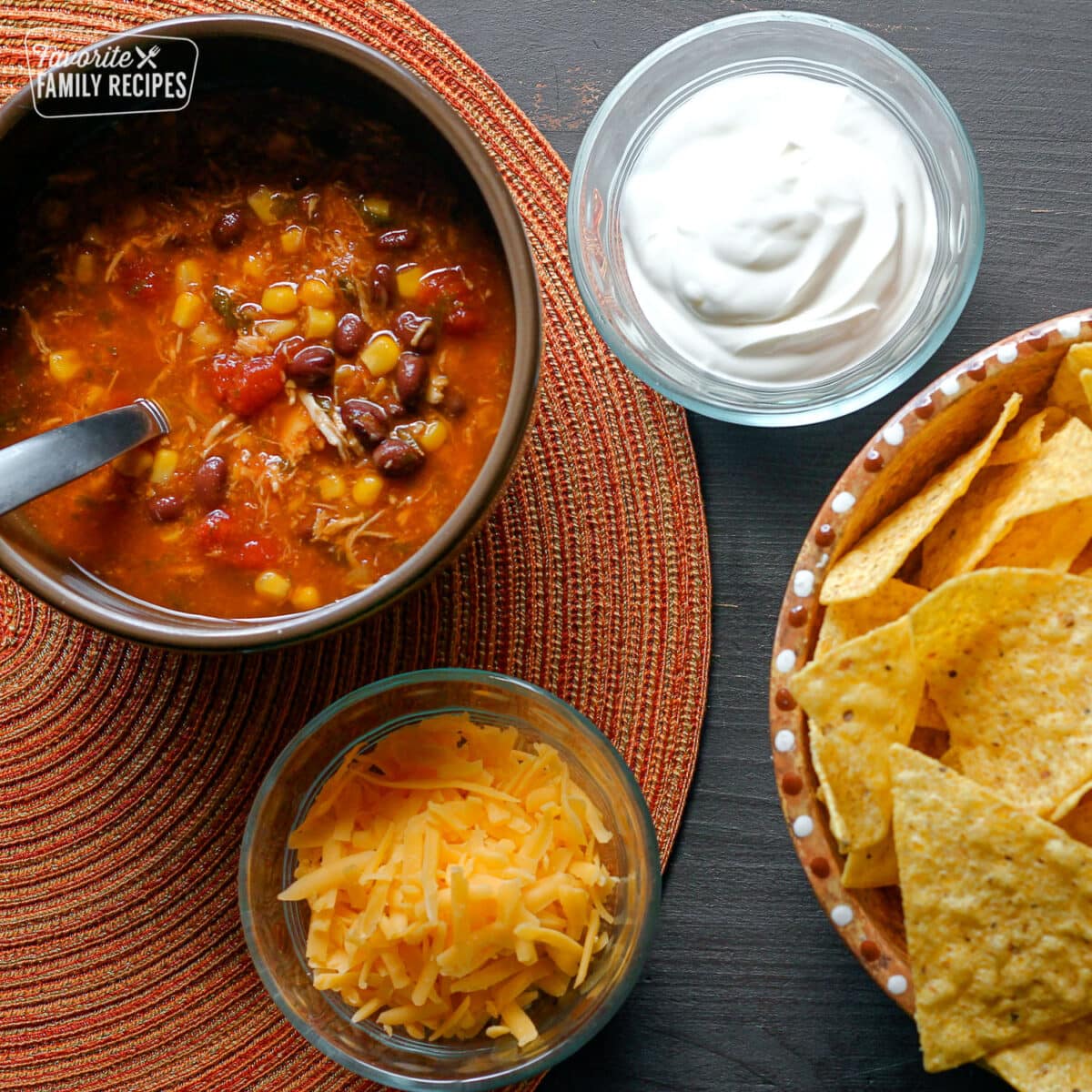 Southwest Taco Soup in a bowl with sour cream, cheese, and chips on the side.