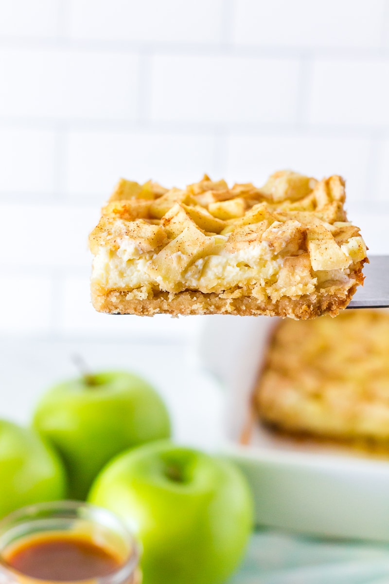Serving spatula holding up a slice of Salted Caramel Apple Cheesecake Bar.