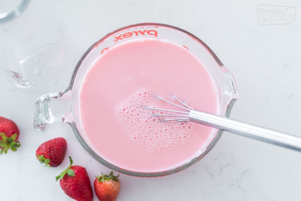 W liquid measuring cup with milk and strawberry syrup combined to make strawberry milk