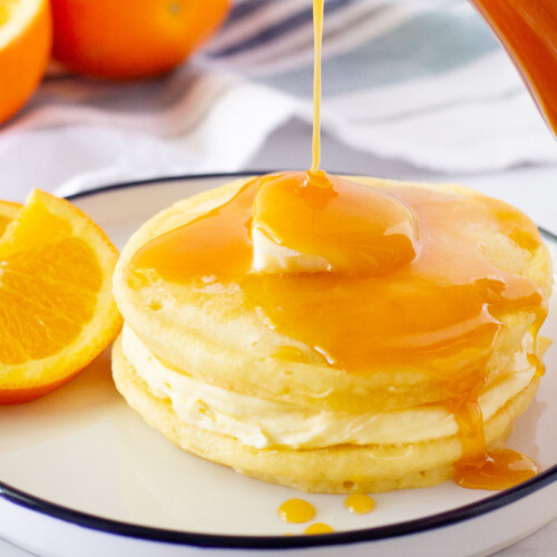 Orange Syrup pouring on top of two Orange Pancakes.