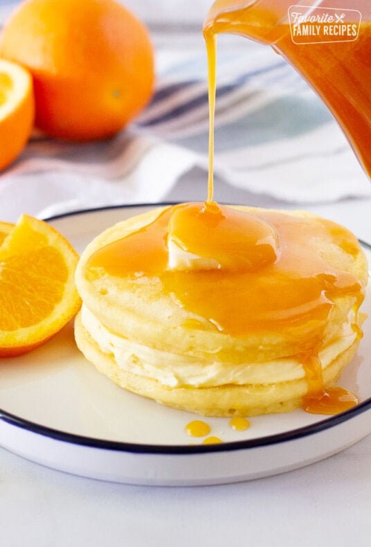 Orange Syrup pouring on top of two Orange Pancakes.