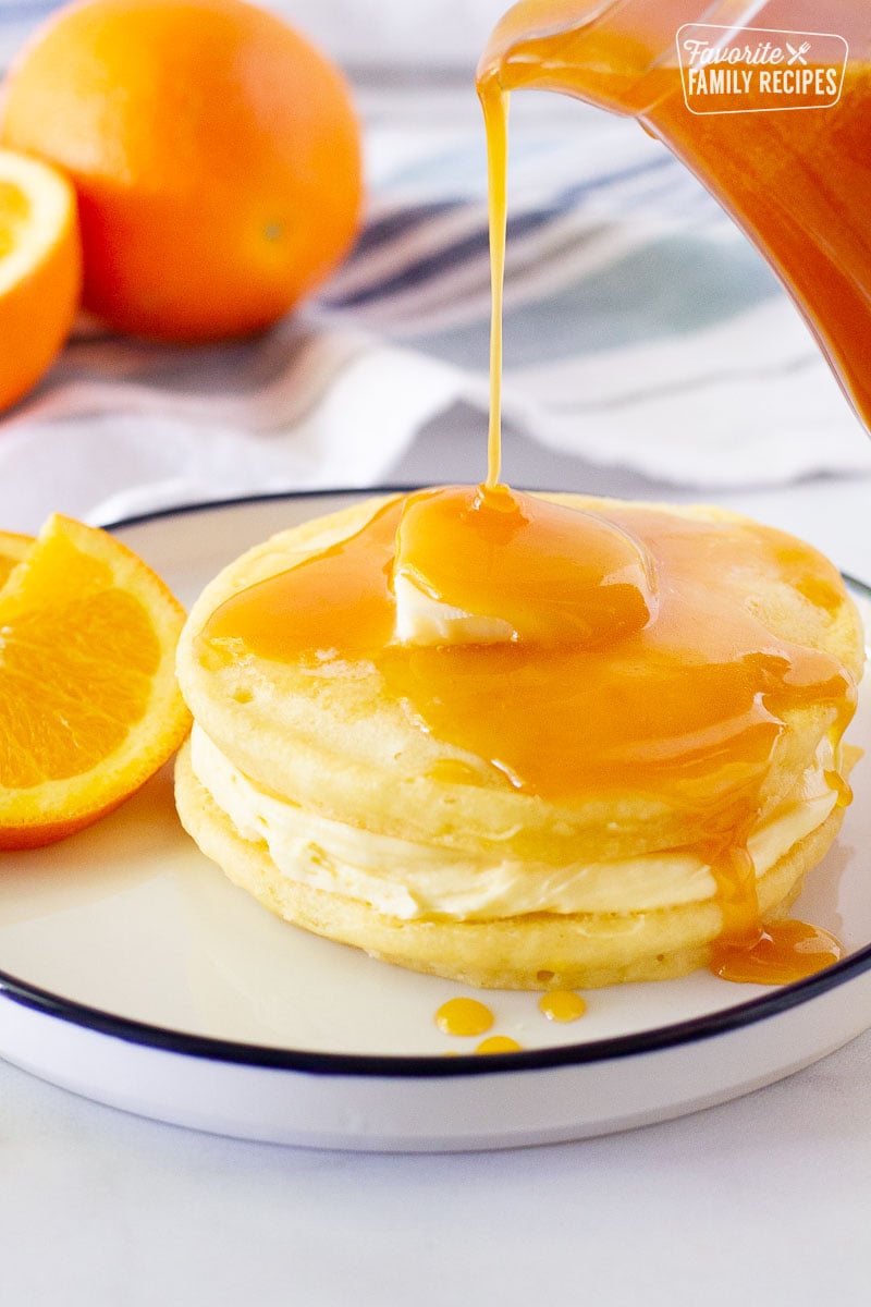 Orange Syrup pouring on top of two Orange Pancakes.