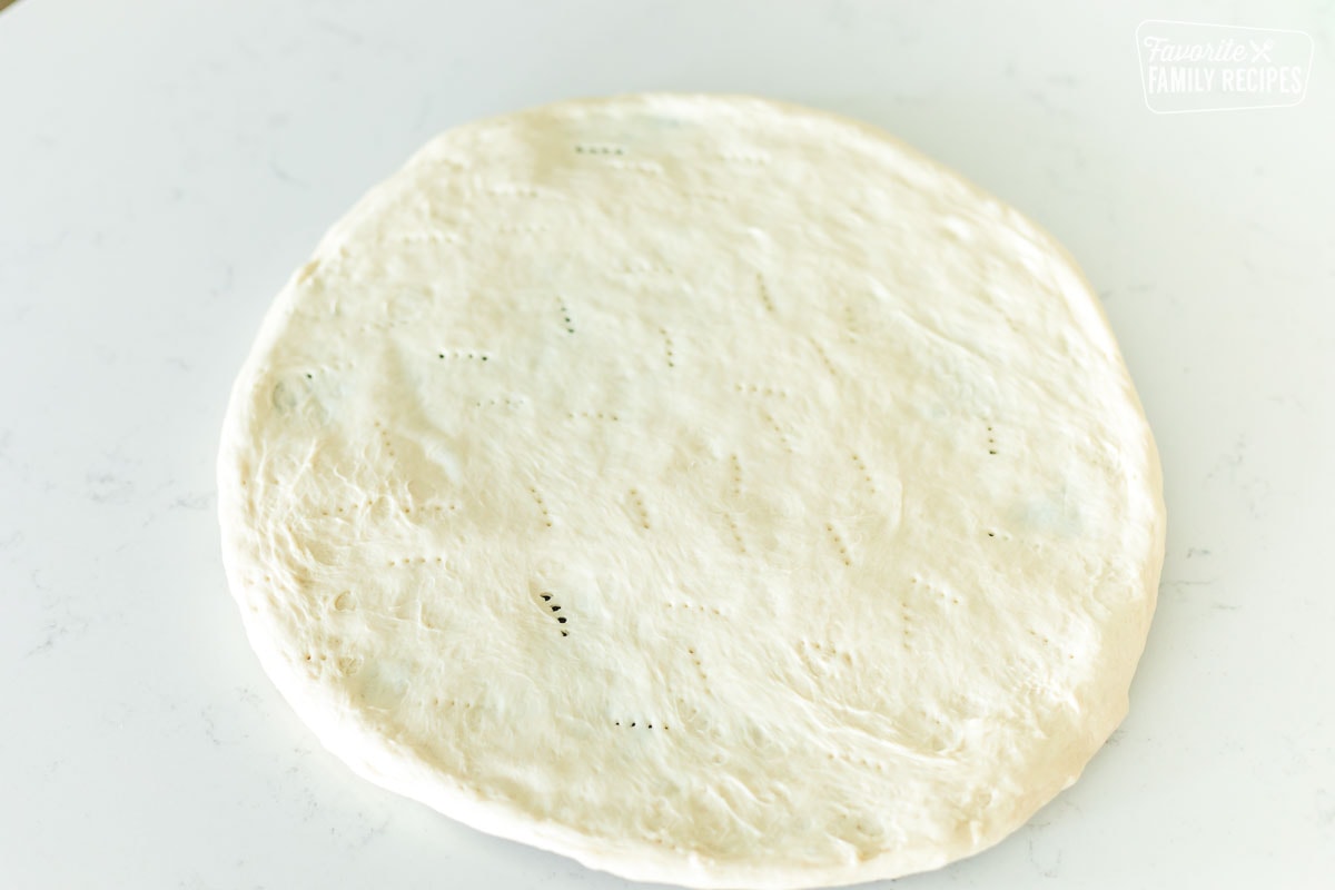 Pizza dough stretched onto a pizza stone.