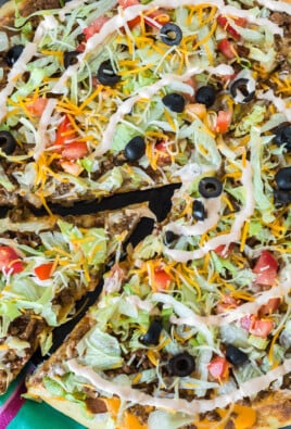A slice of taco pizza being lifted from a whole pizza