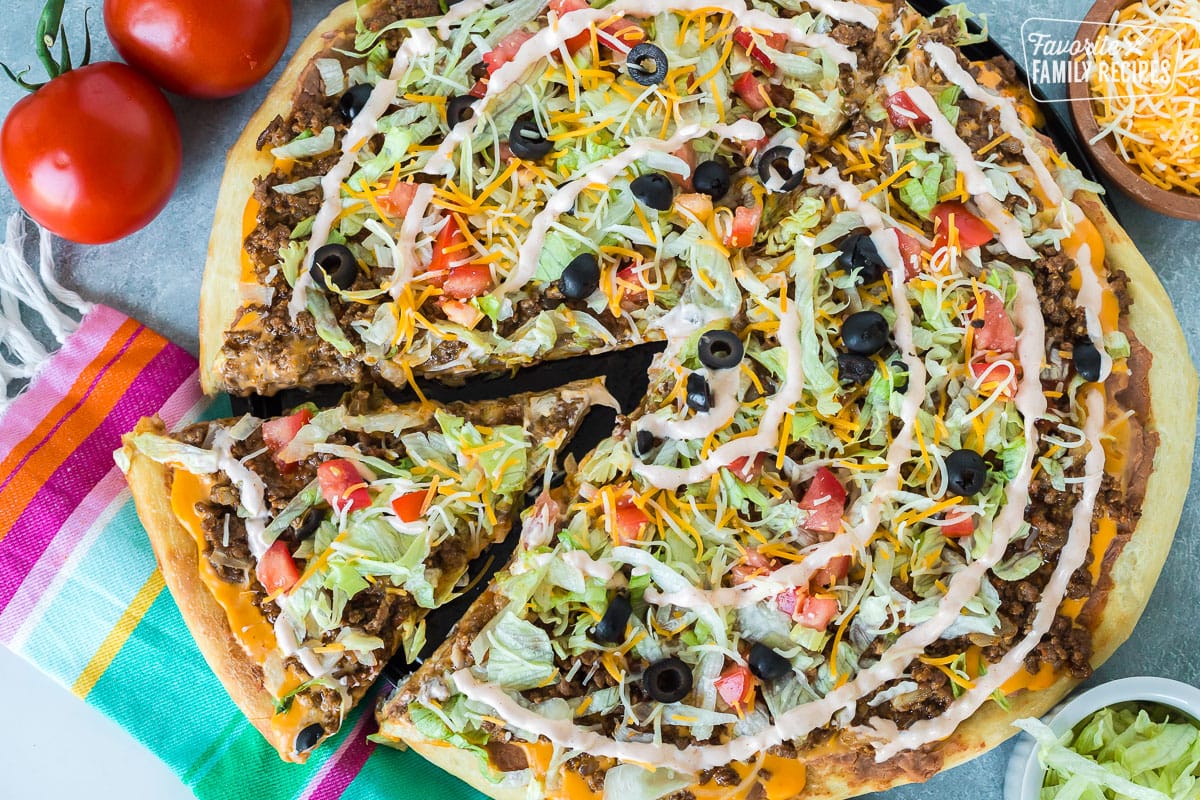 A slice of taco pizza being lifted from a whole pizza