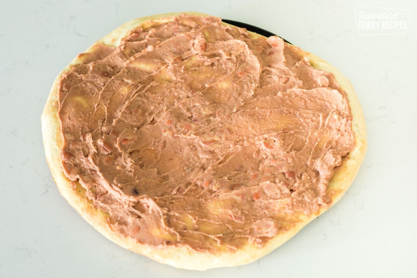 Refried beans spread on a pizza crust
