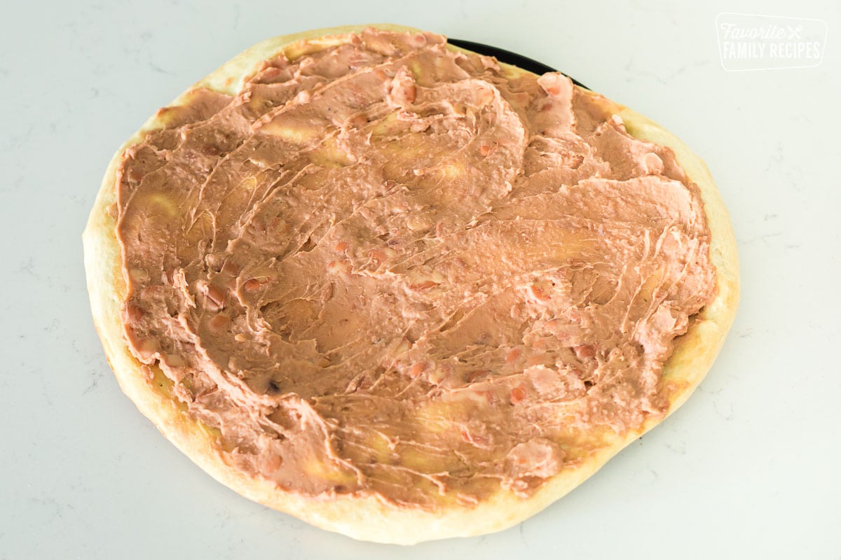 Refried beans spread on a pizza crust.