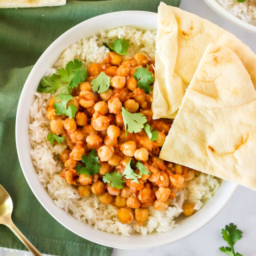 Top view of Curried Chickpeas in a rice bowl with two slices of Naan bread.