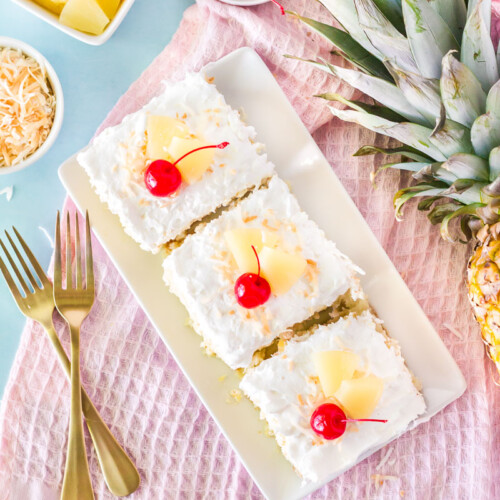 Top view of three slices of Pina Colada Cake. Garnished with cherries, sliced pineapple and toasted coconut.