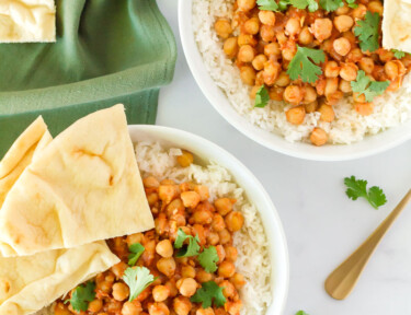 Two bowls of Curried Chickpeas with rice, cilantro and Naan bread.