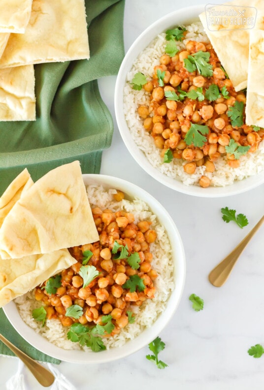 Two bowls of Curried Chickpeas with rice, cilantro and Naan bread.