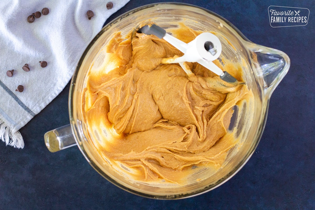 Glass mixing bowl of vanilla and eggs combined in the Peanut Butter Chocolate Chip Cookie dough.