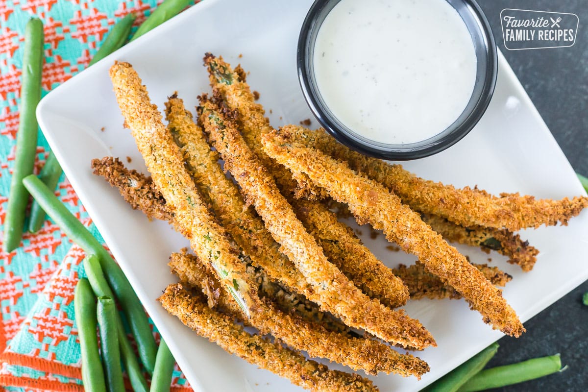 Air fryer green bean fries next to a cup of ranch dressing