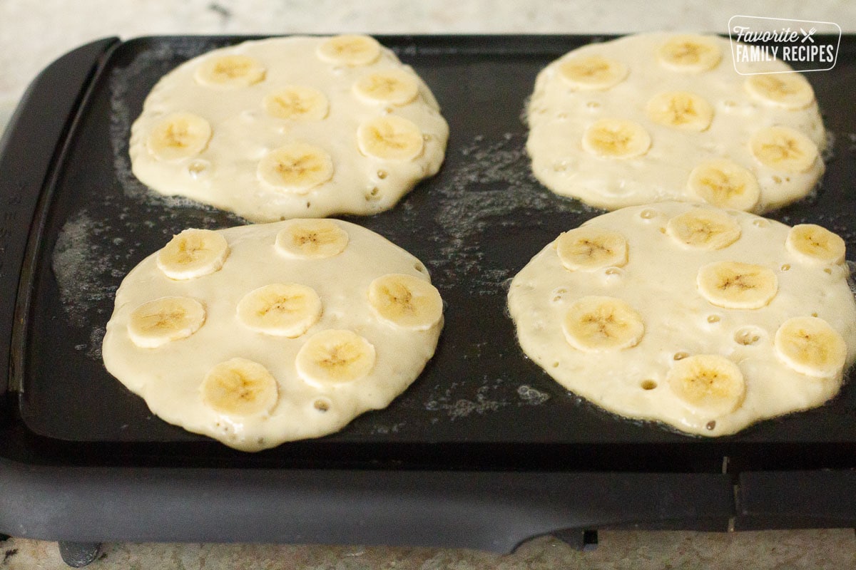 Four Banana Pancakes cooking on the griddle.