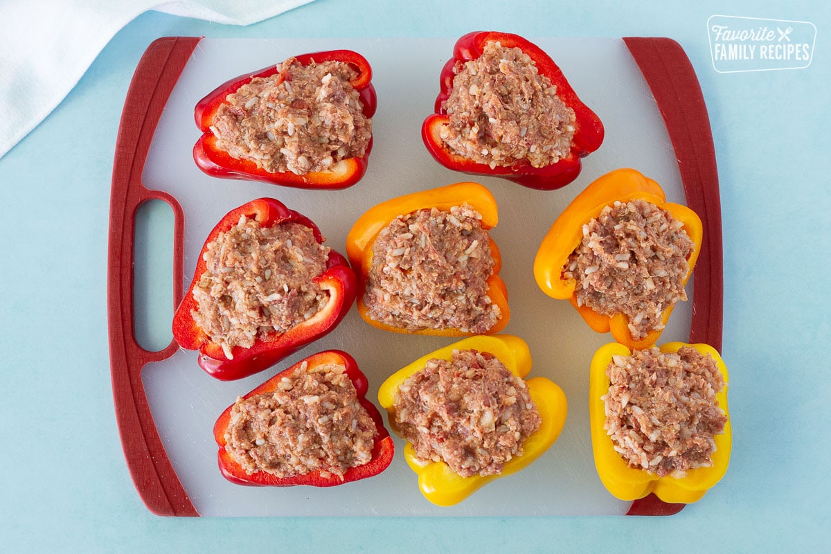 Cutting board with uncooked stuffed bell peppers for Instant Pot Stuffed Peppers.