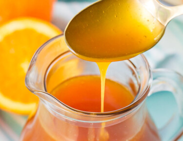 Close up of Orange Syrup drizzling from a golden spoon.