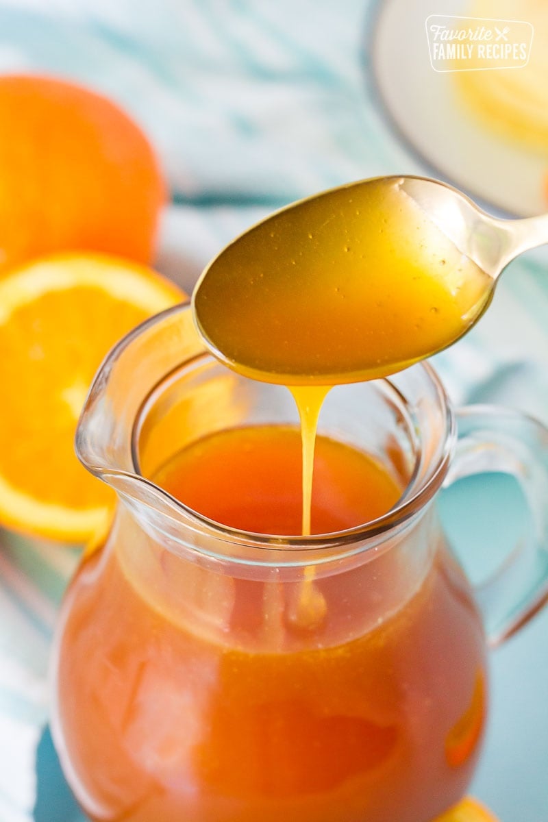 Close up of Orange Syrup drizzling from a golden spoon.