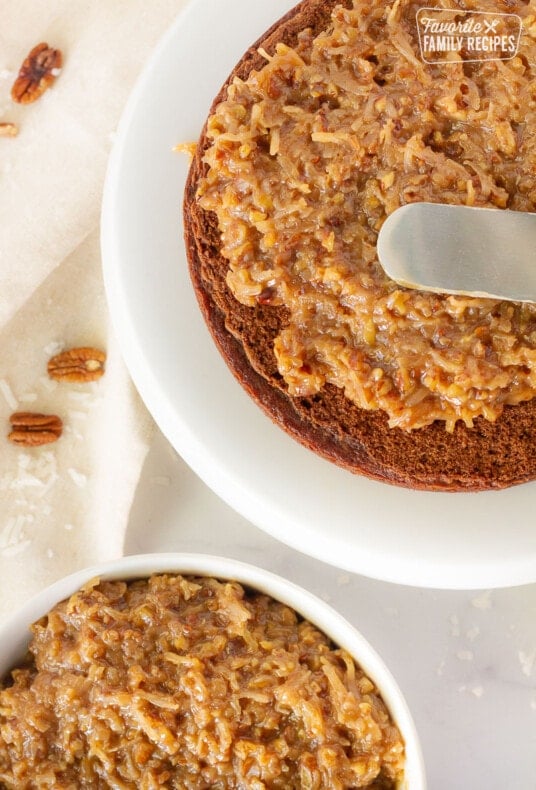 Spatula spreading homemade Coconut Pecan Frosting on a German Chocolate cake.