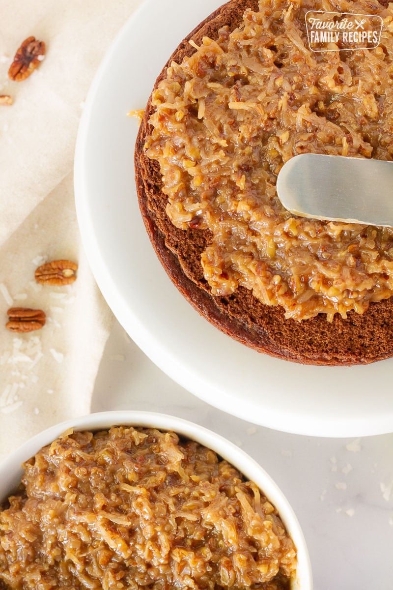 Spatula spreading homemade Coconut Pecan Frosting on a German Chocolate cake.