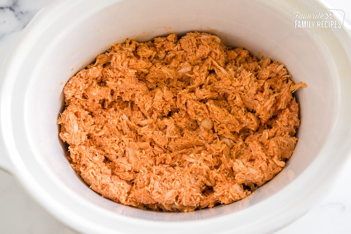 Shredded chicken mixed with hot sauce in a crock pot