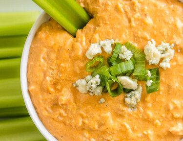 Buffalo chicken dip in a bowl with celery dipped in it