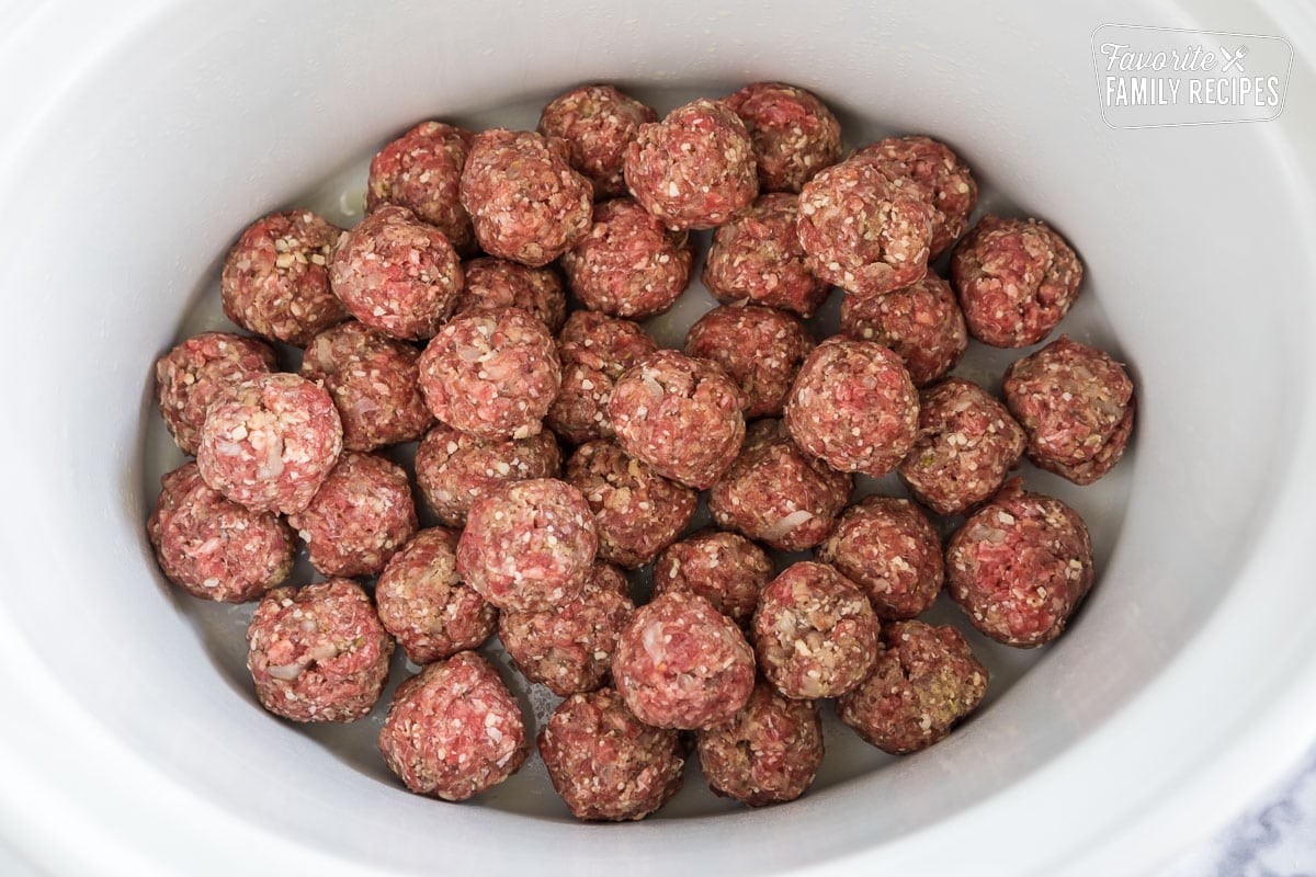 Raw meatballs rolled and placed in a crockpot