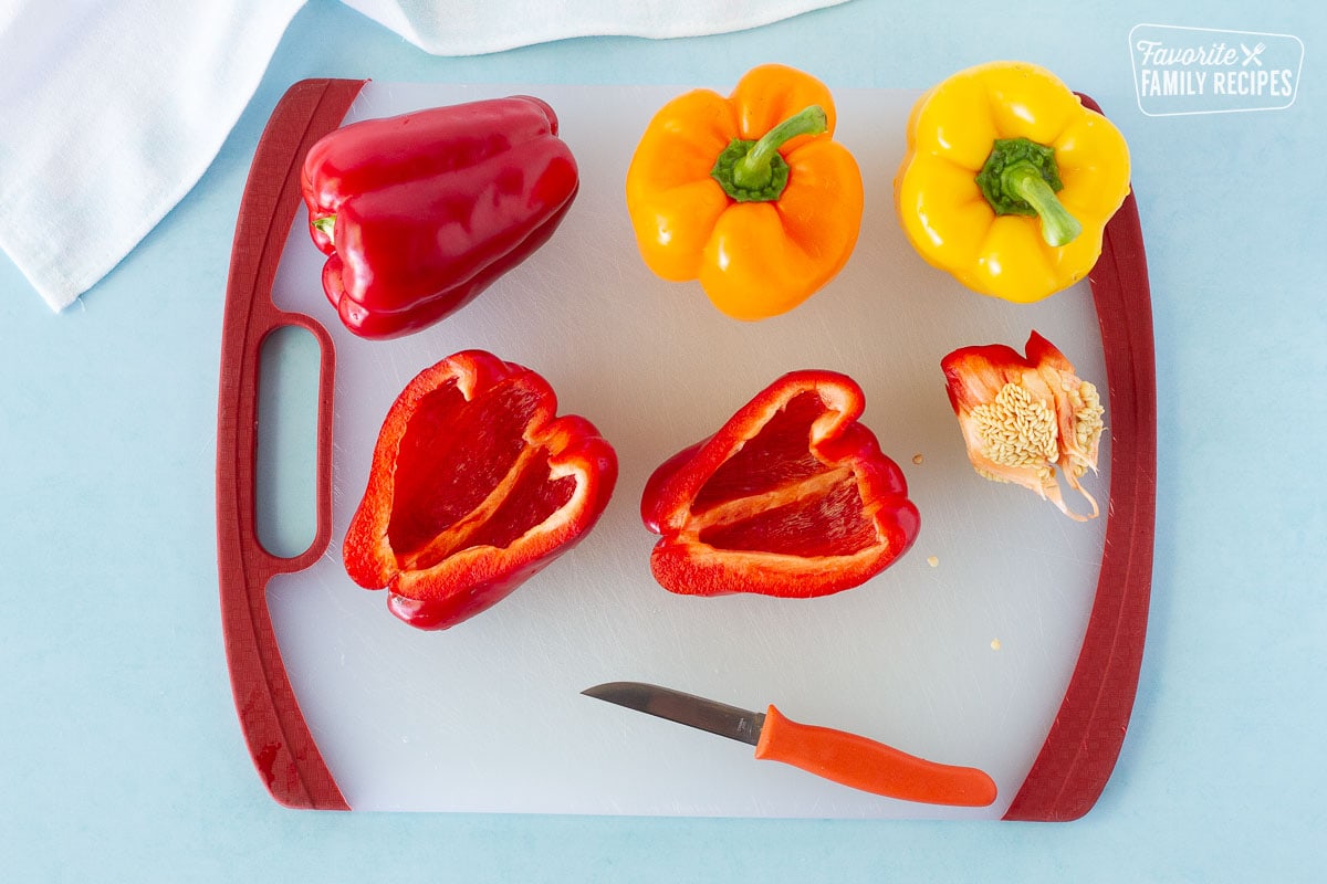 Cutting board with red, orange and yellow bell peppers to make Instant Pot Stuffed Peppers.
