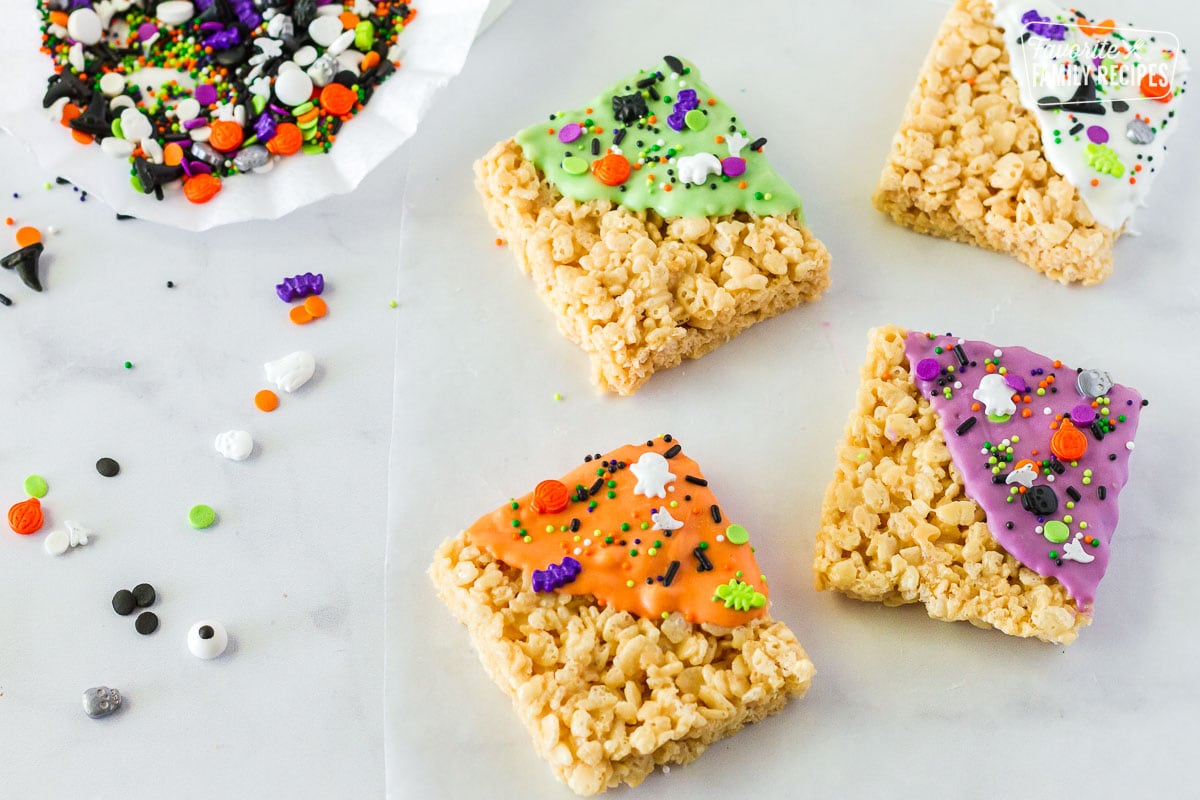 Rice Krispie treat squares that have been dipped in icing and sprinkled with Halloween sprinkles