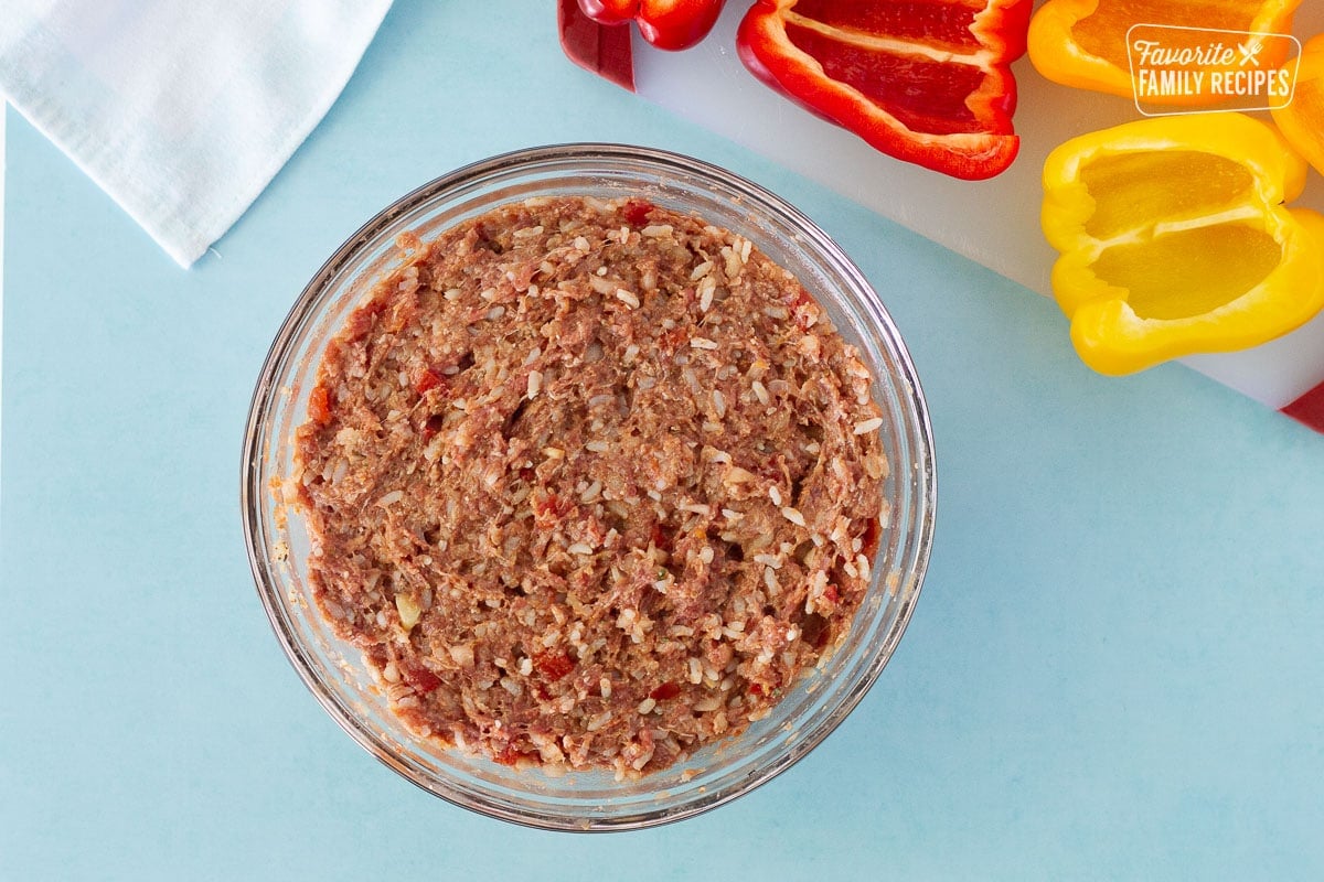 Bowl of ground beef mixture to fill the Instant Pot Stuffed Peppers. Halved bell peppers on the side.