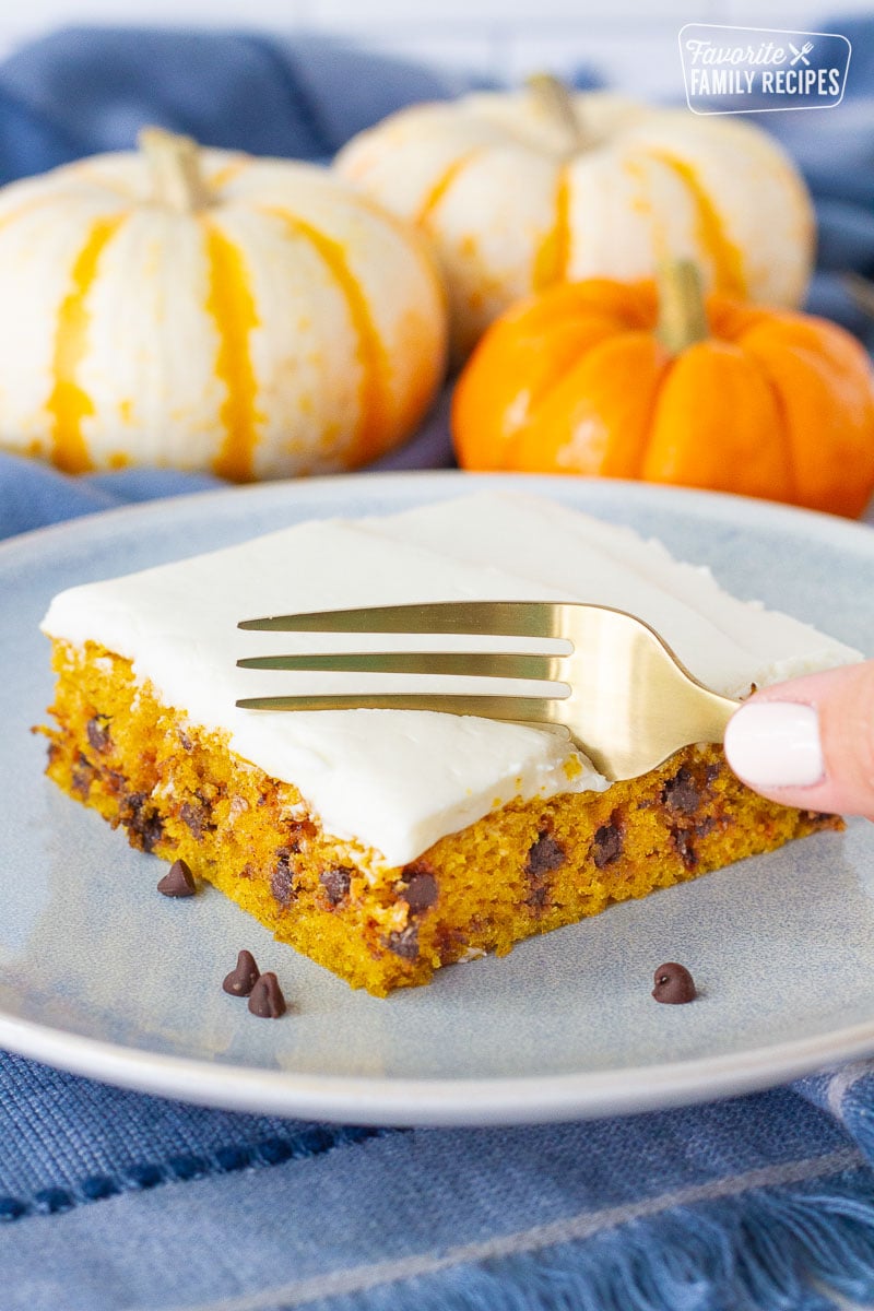 Fork cutting into a slice of Pumpkin Sheet Cake. Mini chocolate chips on the side.