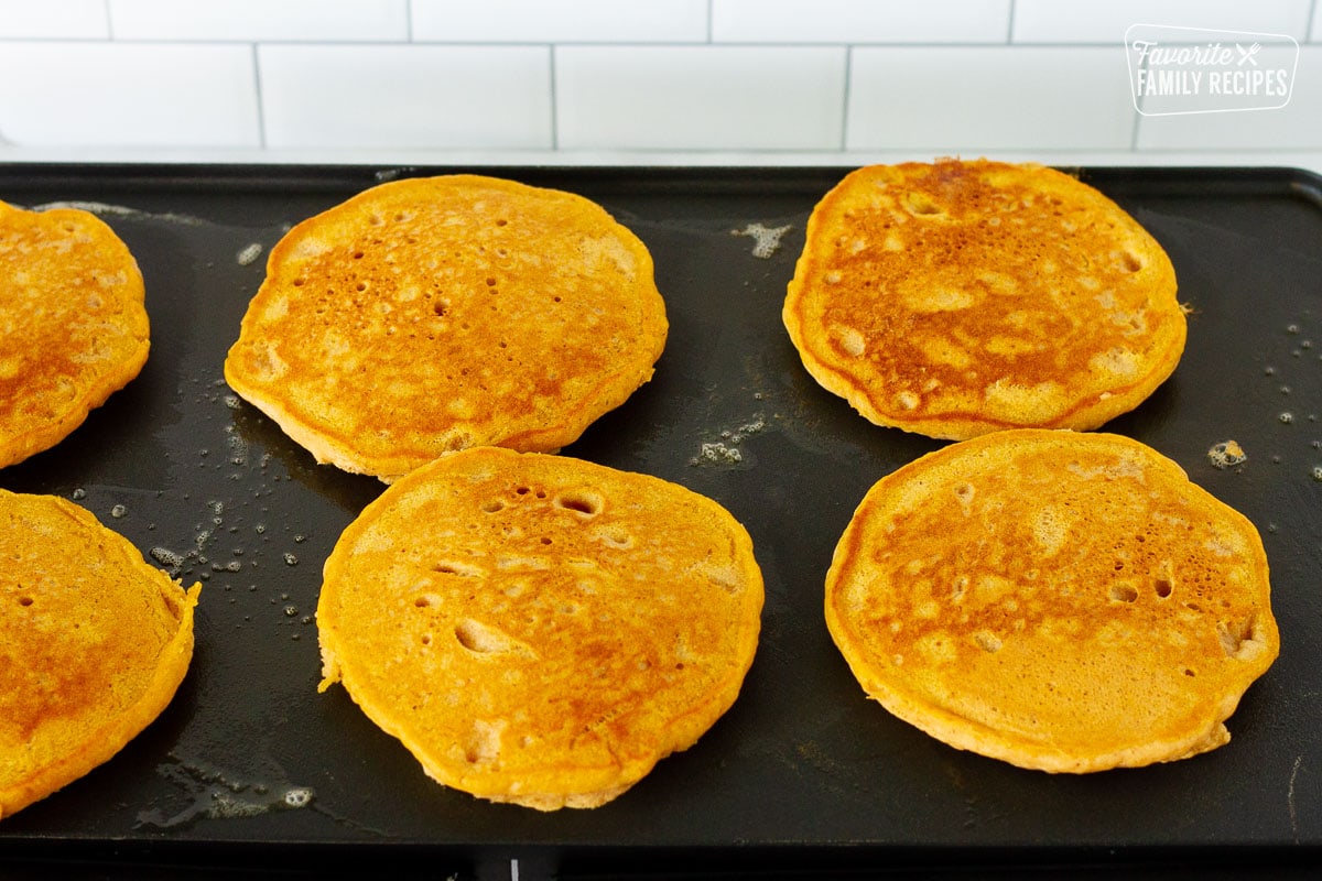 Griddle with flipped Pumpkin Pancakes.