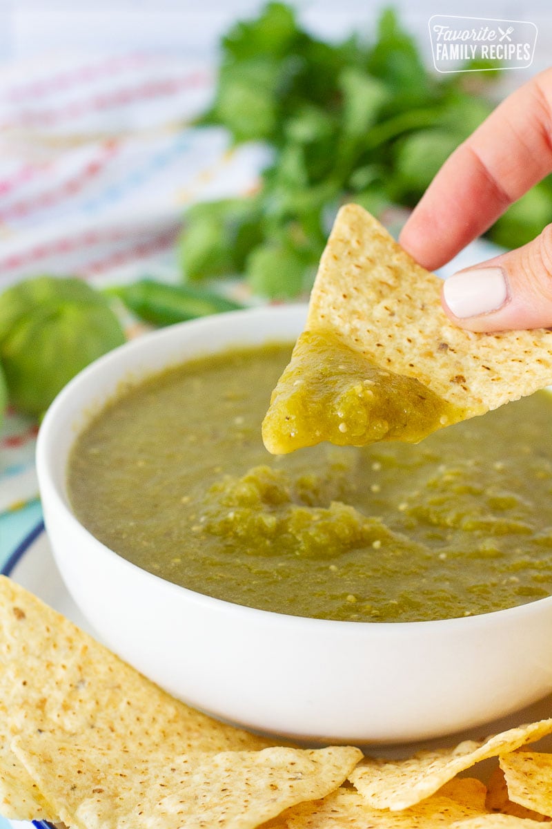 Hand holding a tortilla chip with Tomatillo Salsa Verde.