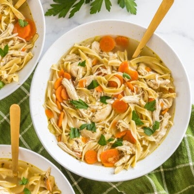 A bowl of chicken noodle soup with a spoon.