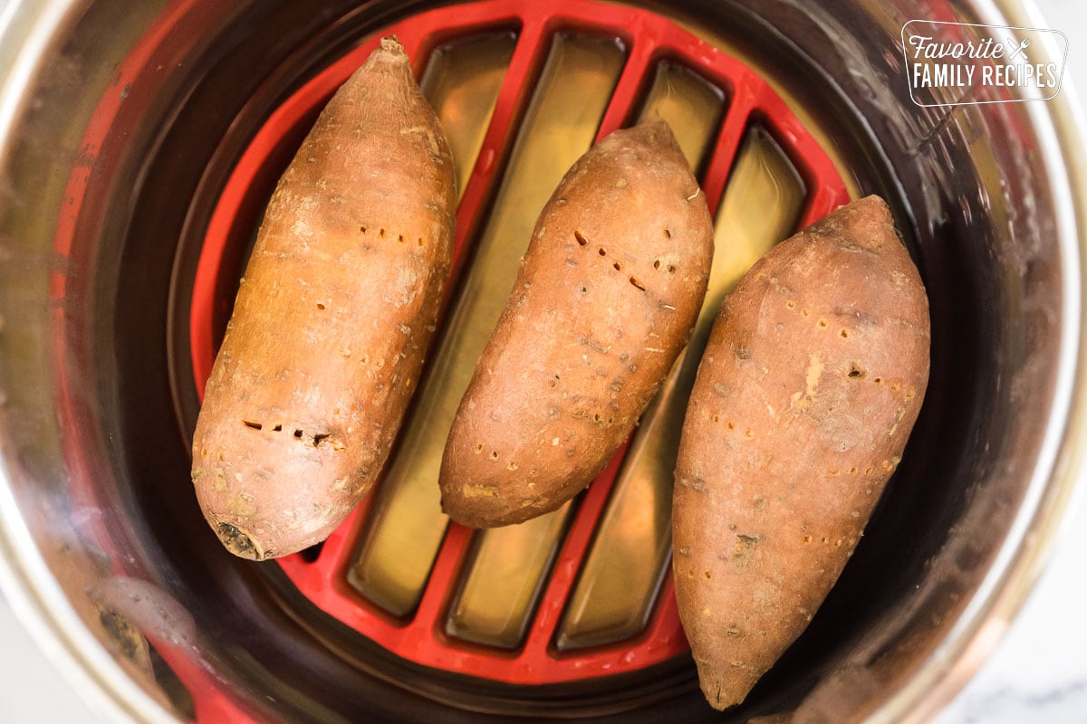 Three cooked sweet potatoes on a trivet in an instant pot