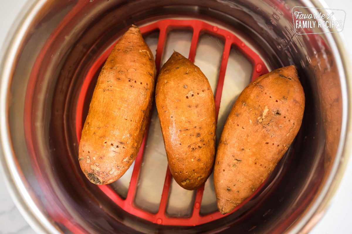 Three raw sweet potatoes on trivet in an instant pot
