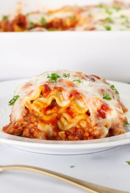 Lasagna Roll Up on a plate with a side of bread and dish.