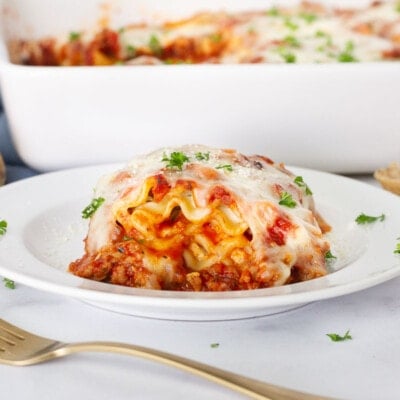 Lasagna Roll Up on a plate with a side of bread and dish.