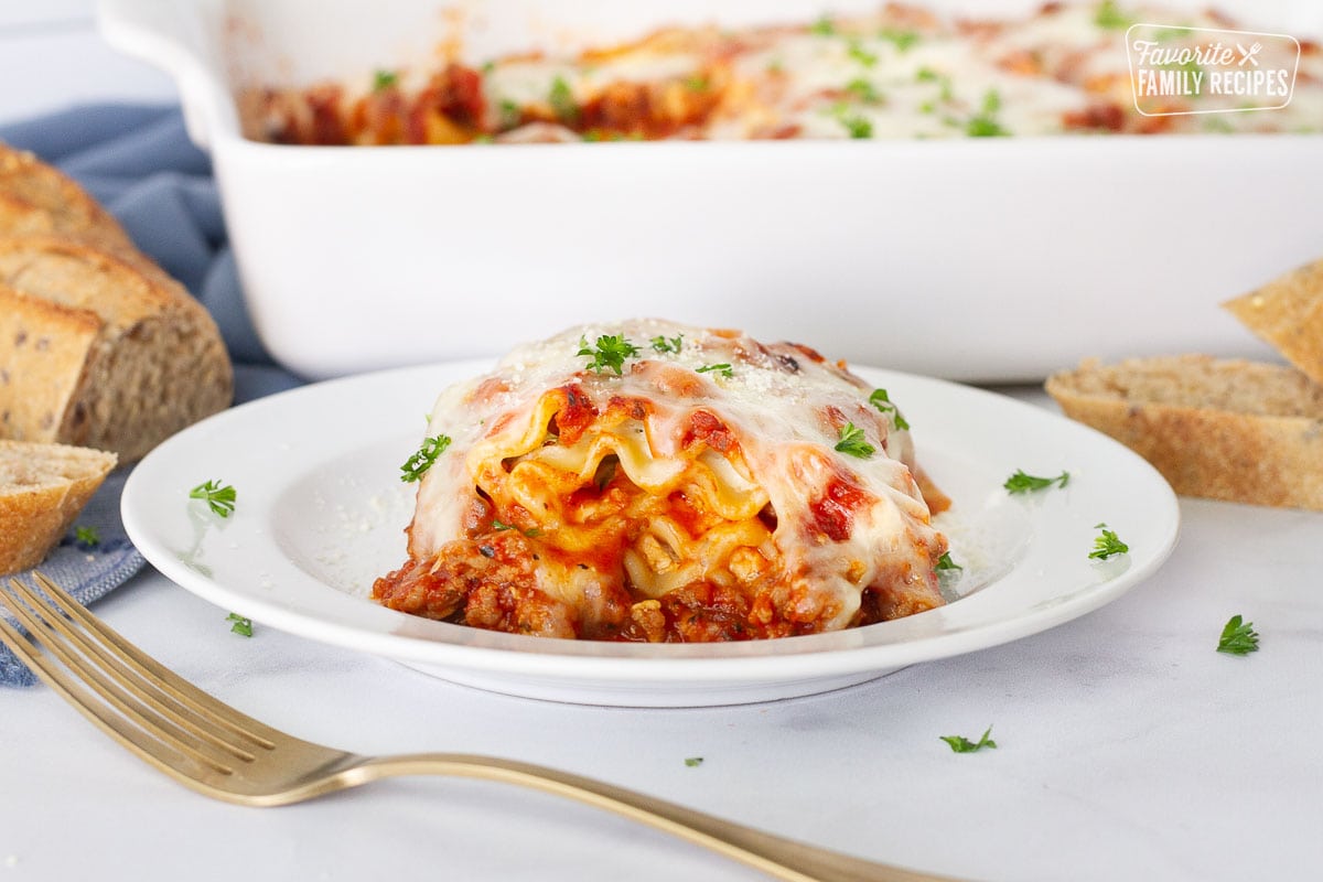 Lasagne Roll Up on a plate with a side of bread and dish.