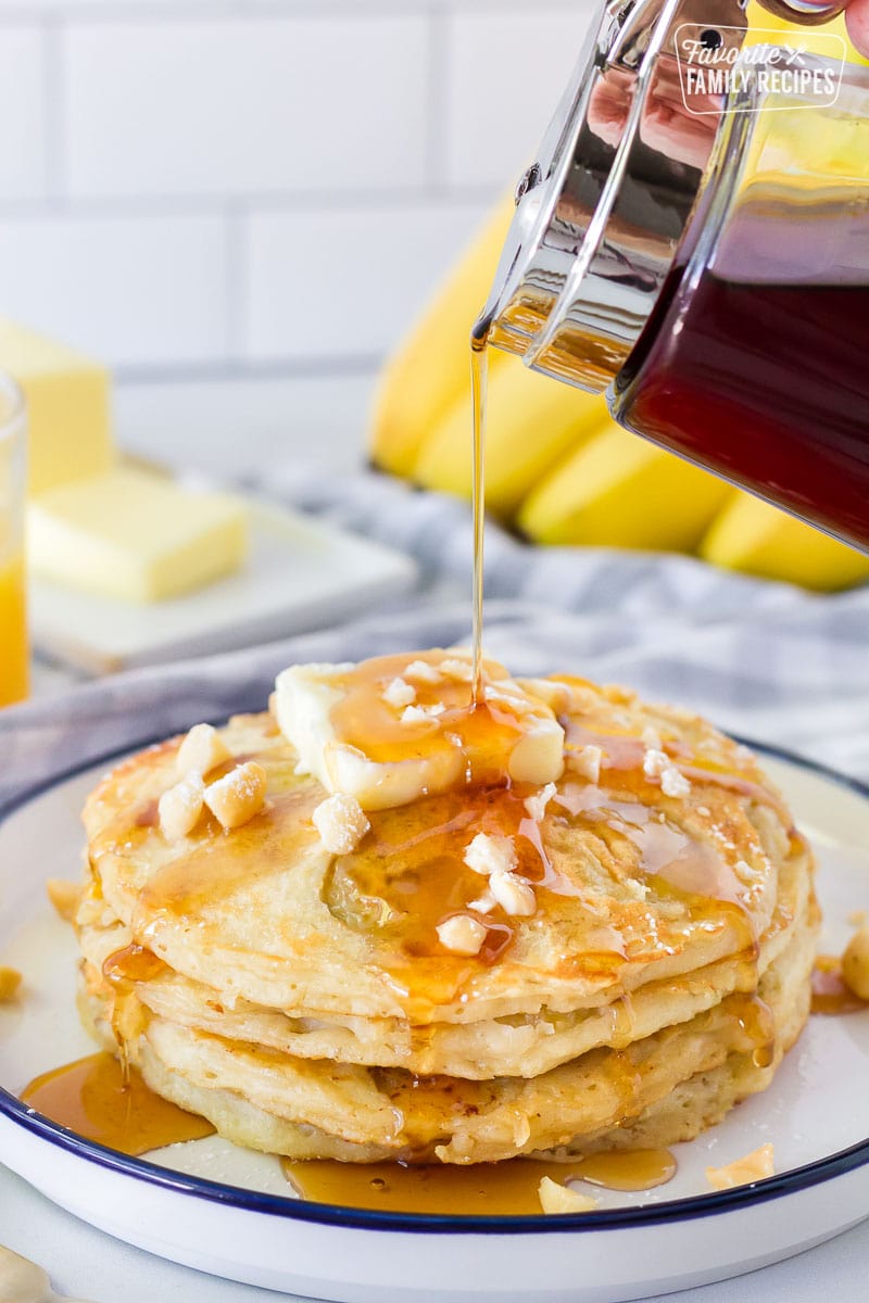 Maple Syrup pouring onto a stack of Banana Pancakes.