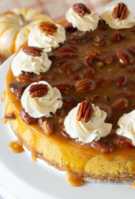 Pumpkin Cheesecake on a cake platter with caramel pecan and whipped cream.