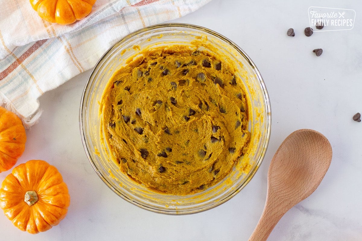 Bowl of Pumpkin Chocolate Chip Cookie dough. Wooded spoon on the side.