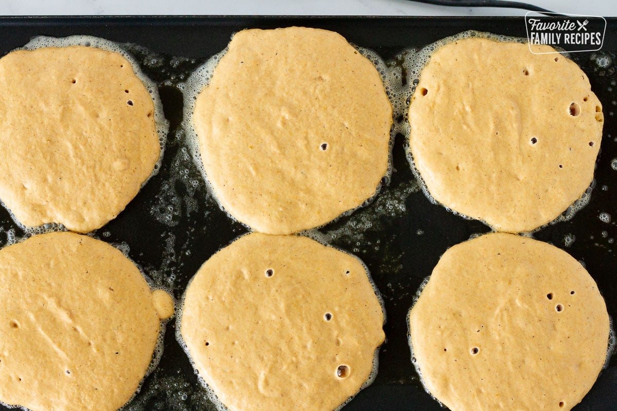 Pumpkin pancakes cooking on the griddle.