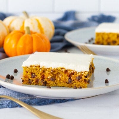 Side view of two slices of Pumpkin Sheet Cake on serving plates with spoons.