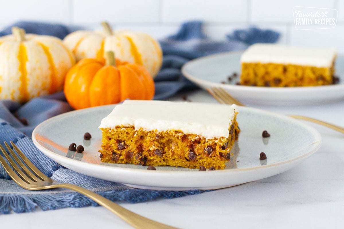 Side view of two slices of Pumpkin Sheet Cake on serving plates with spoons.