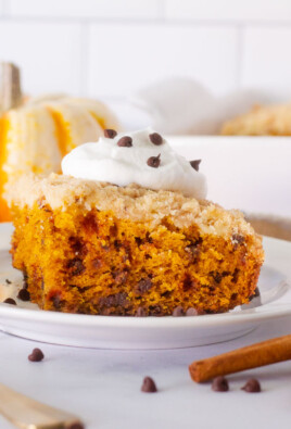 Slice of Pumpkin Coffee Cake on a plate topped with whipped cream and mini chocolate chips.