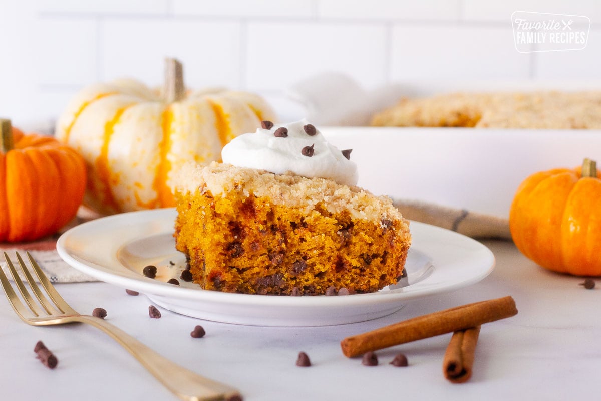 Slice of Pumpkin Coffee Cake on a plate topped with whipped cream and mini chocolate chips.