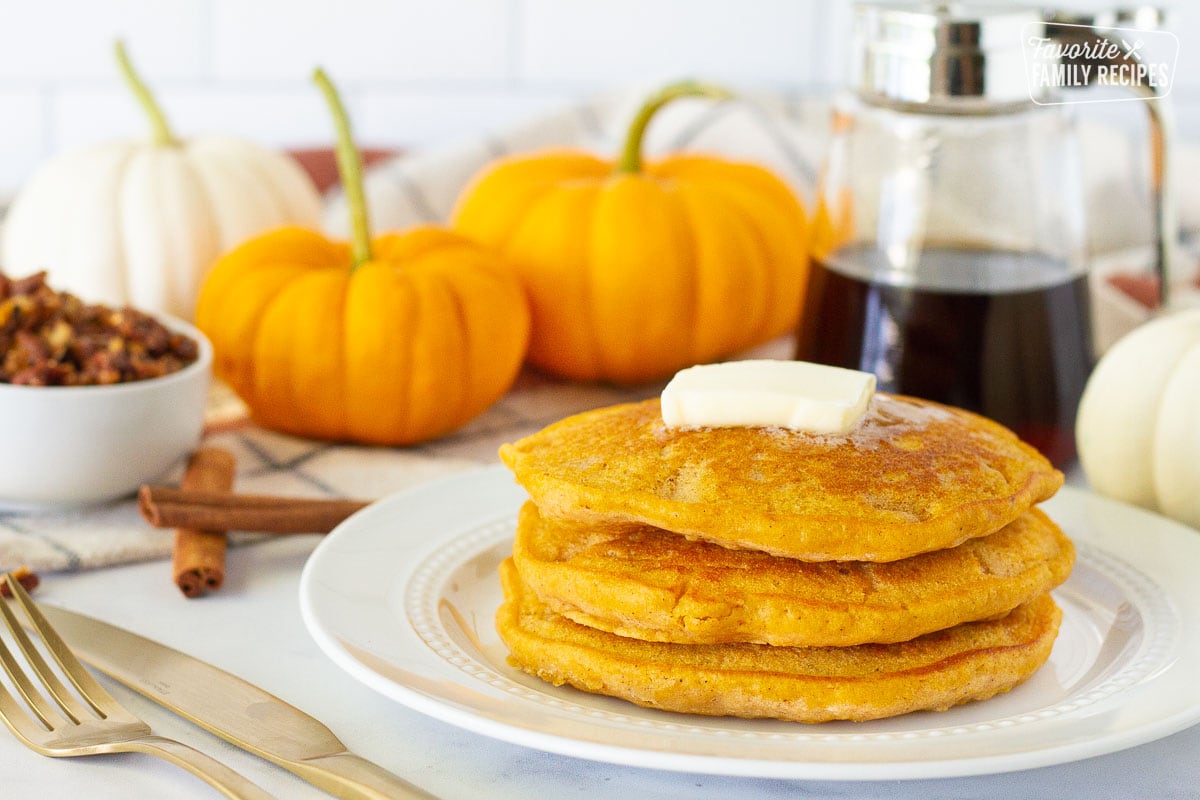 Side view of stacked Pumpkin Pancakes with a pad of butter.