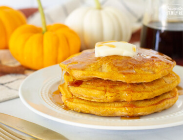 Three Pumpkin Pancakes with butter and syrup.