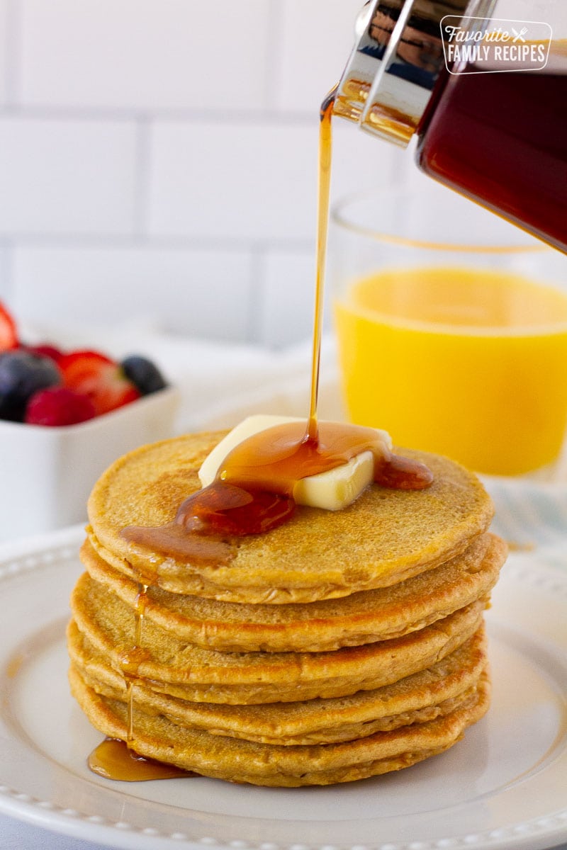 Maple syrup pouring onto stack of Whole Wheat Pancakes.
